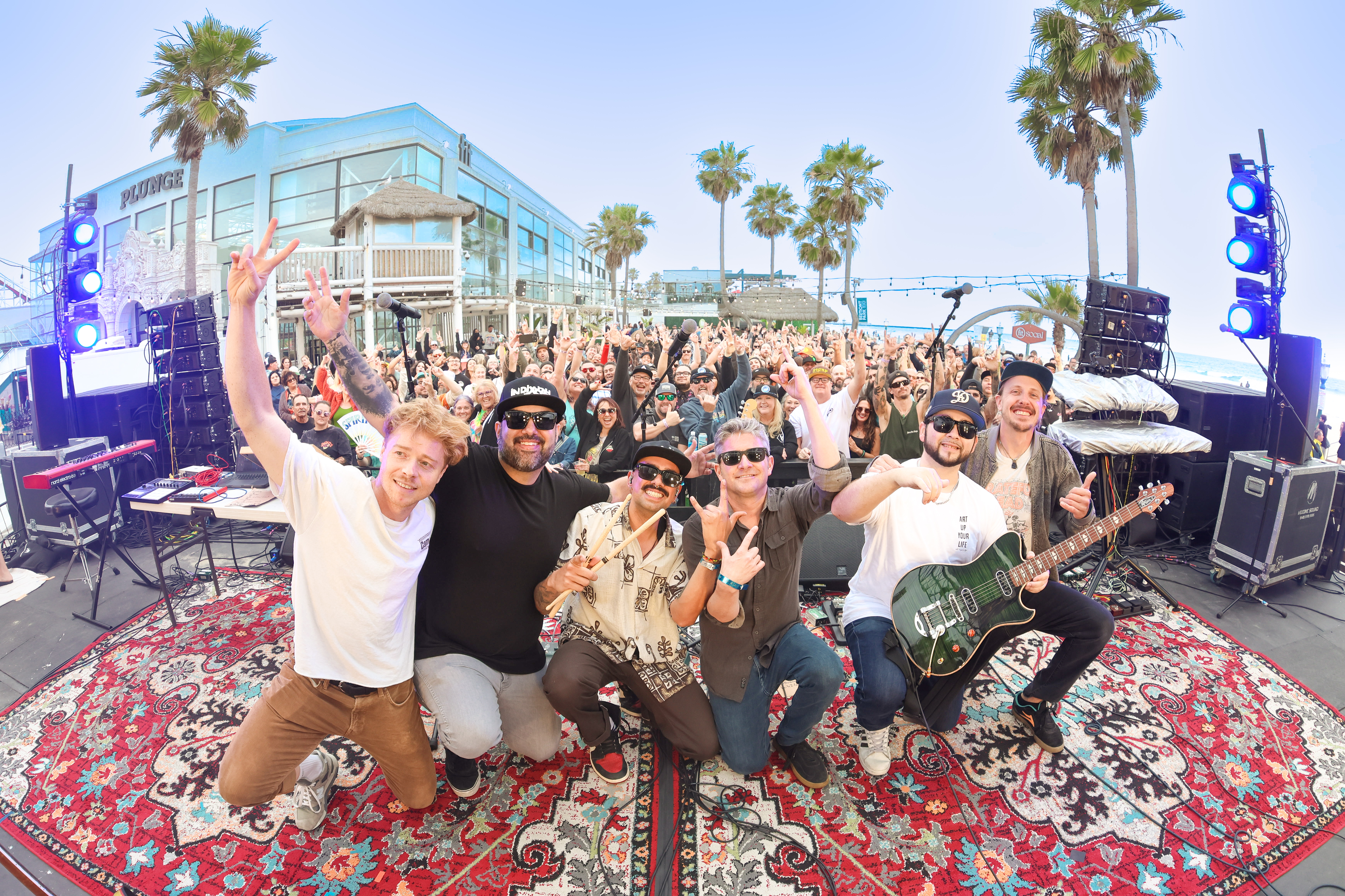 Alific and the full live band gathered with the audience on a patterned rug at The Beach House, San Diego