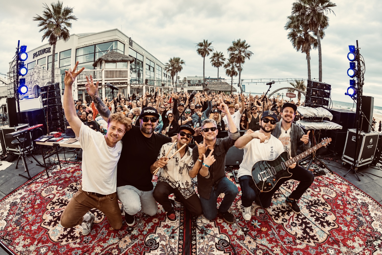 The band and friends gathered on a patterned rug at Fit Social, San Diego