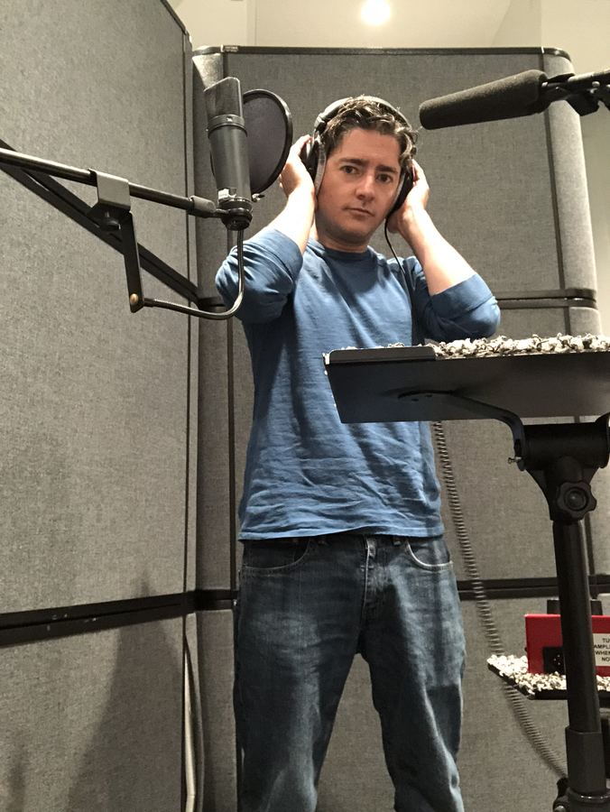 Musician leaning back with headphones beside an overhead microphone