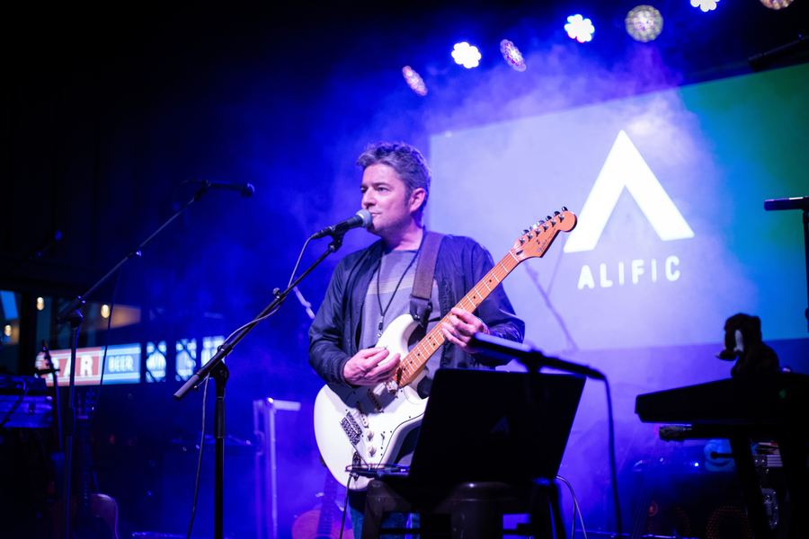 Full stage under purple lights, Alific backdrop behind the band